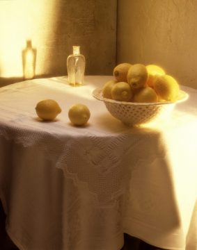 10 a bowl of lemons on a table with a streak of sunlight