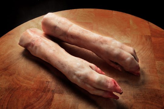 7 s pair of raw pigs feet (trotters) on a butchers block